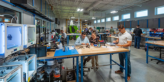 Engineers working with computers and machinery in Kinetic Vision prototype lab